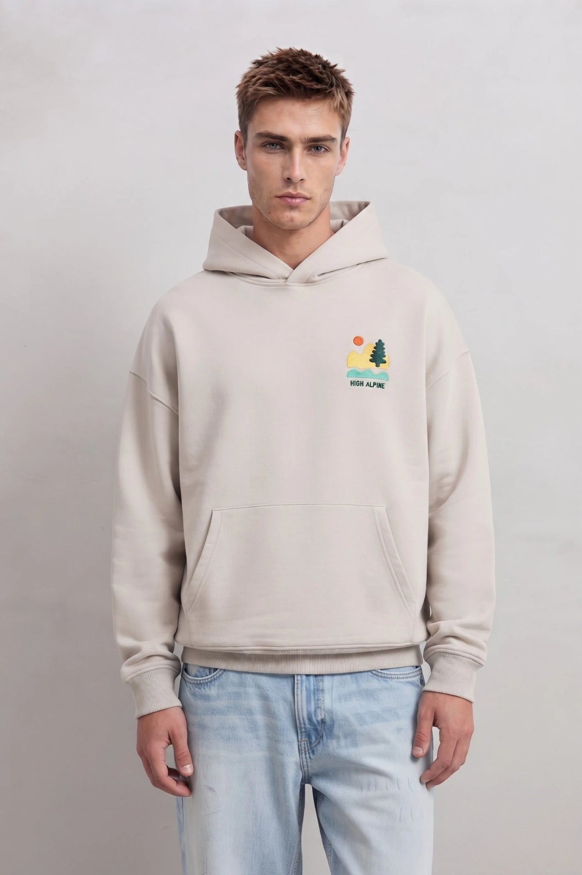 Sudadera beige oversize de hombre con capucha y pequeño paisaje High Alpine en el pecho
