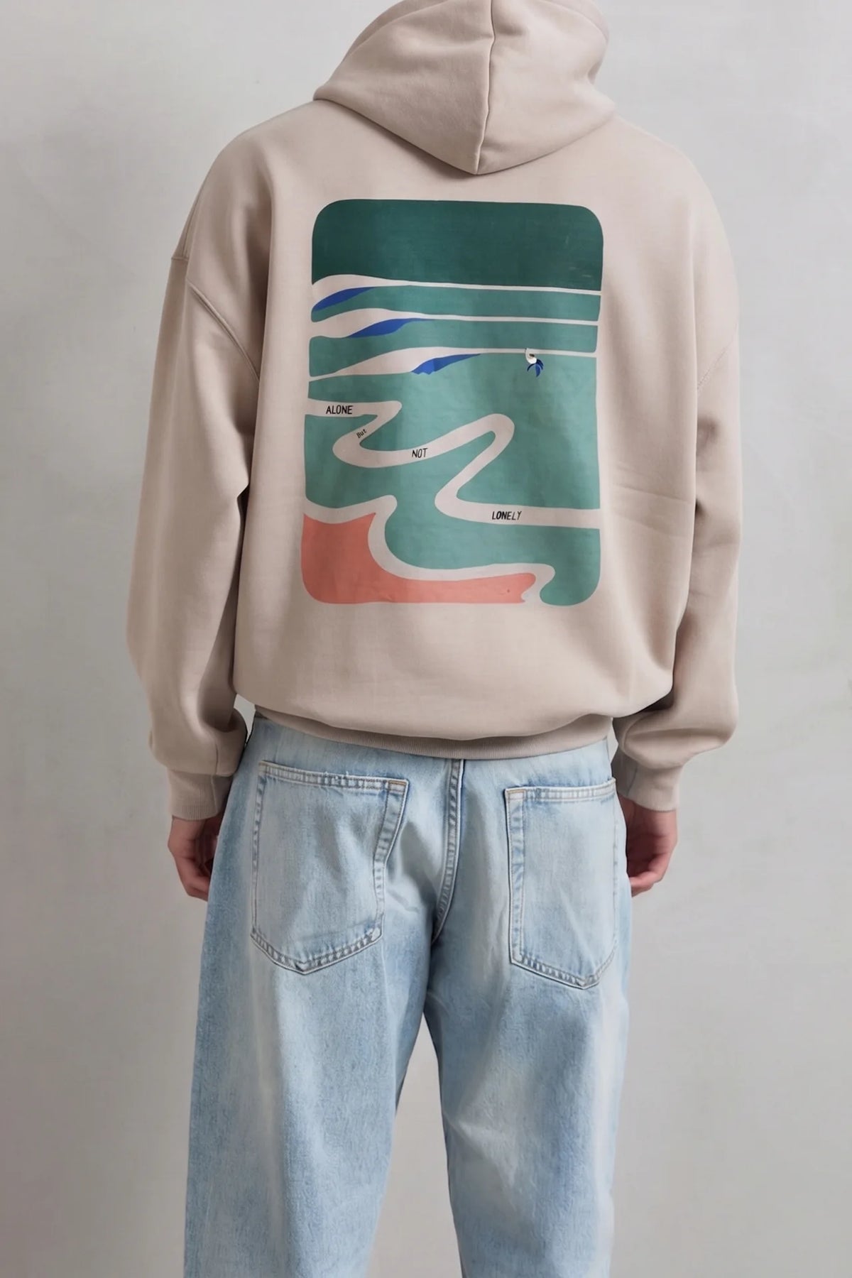 Espalda de sudadera beige con paisaje abstracto verde y camino sinuoso en tonos crema azul y terracota