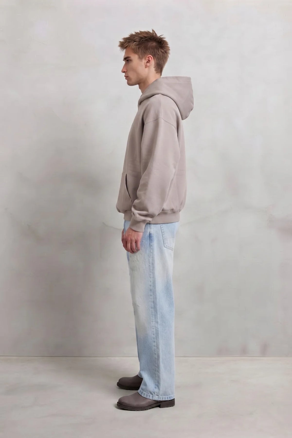 Vista lateral de cuerpo entero con sudadera beige oversize con capucha y vaqueros claros