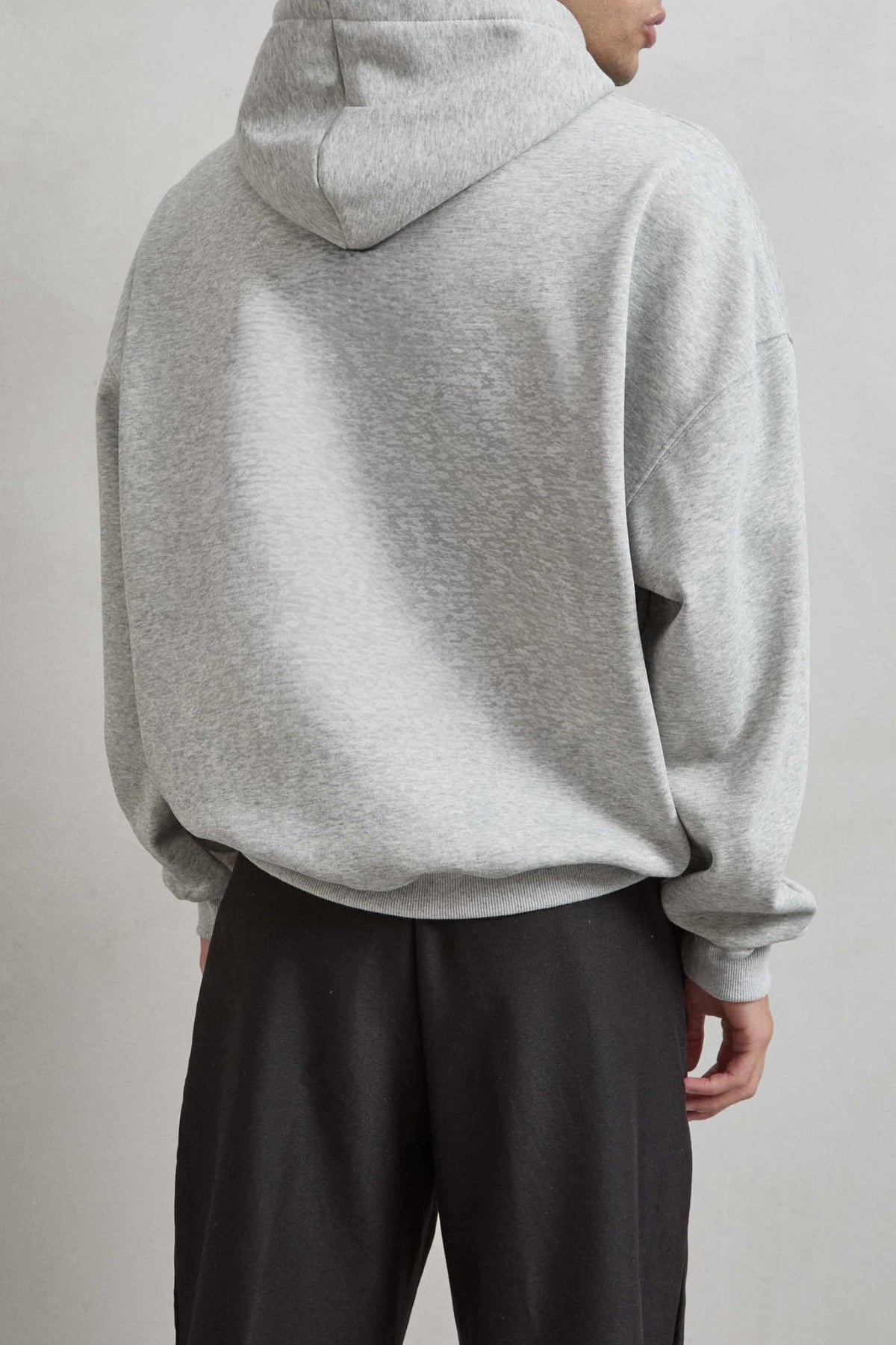 Vista posterior de medio cuerpo de sudadera gris jaspe con capucha y espalda lisa