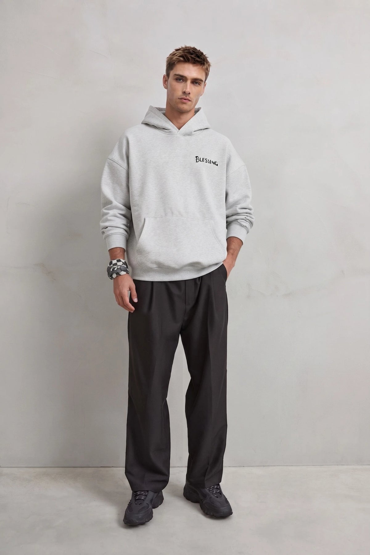 Vista frontal de cuerpo entero con sudadera gris Blessing y pantalones negros