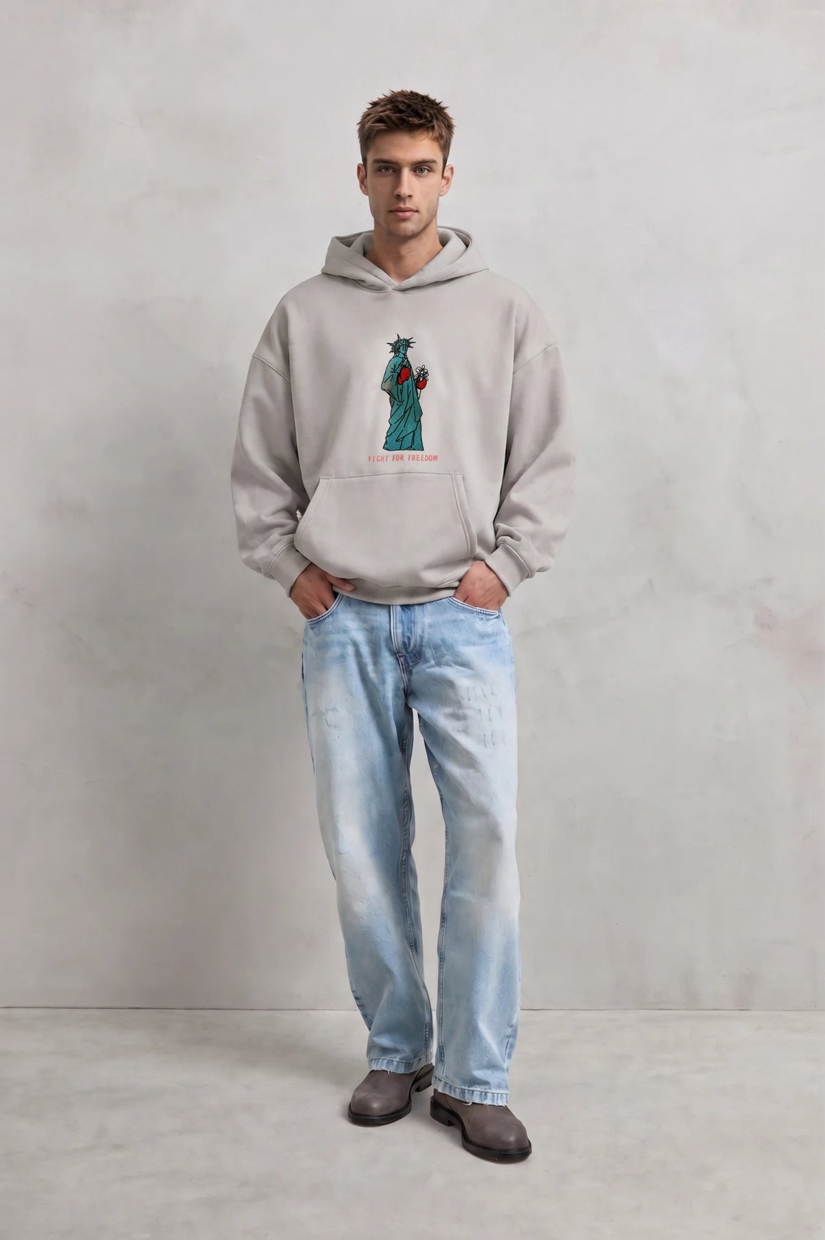 Vista frontal de cuerpo entero con sudadera gris claro Fight for Freedom y vaqueros