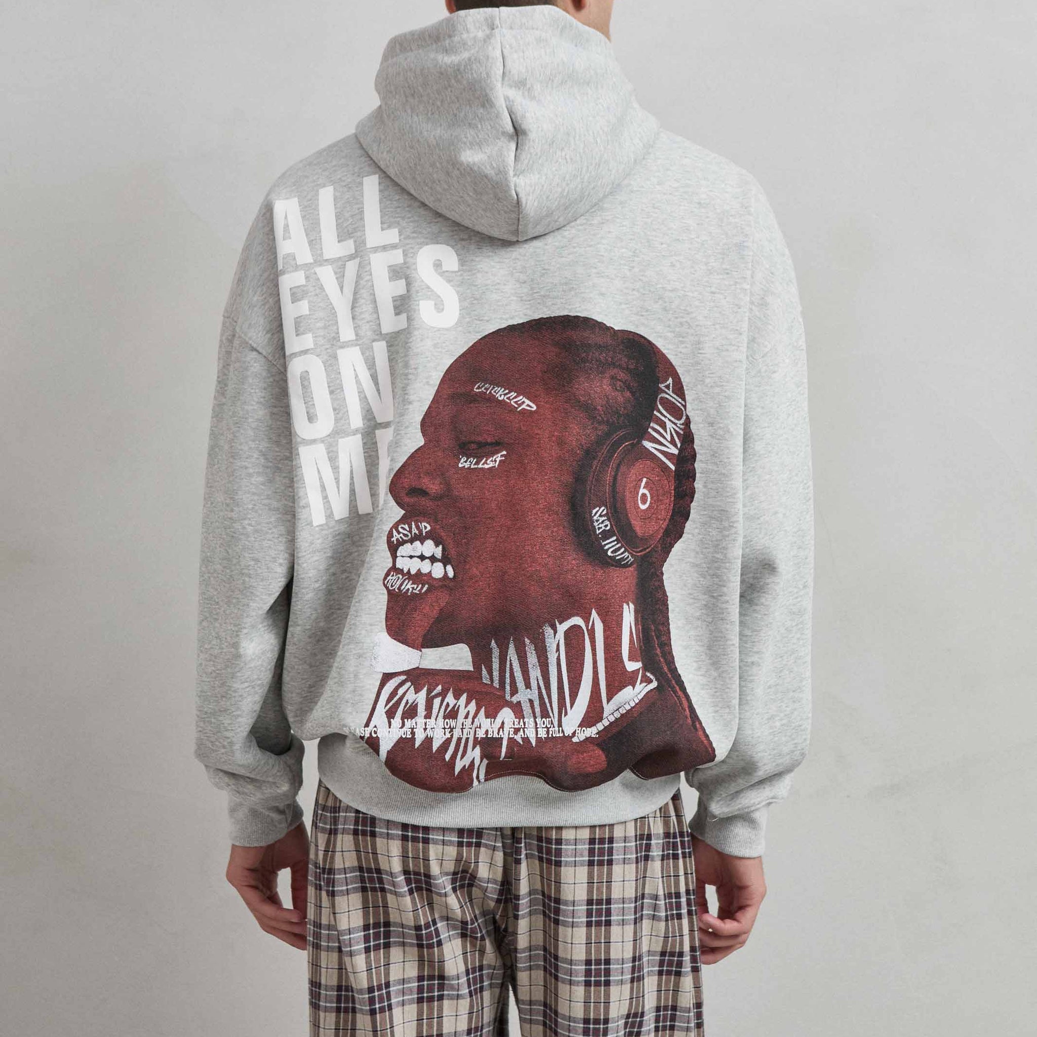 Vista trasera de sudadera gris jaspe con gráfico “ALL EYES ON ME” y rostro expresivo