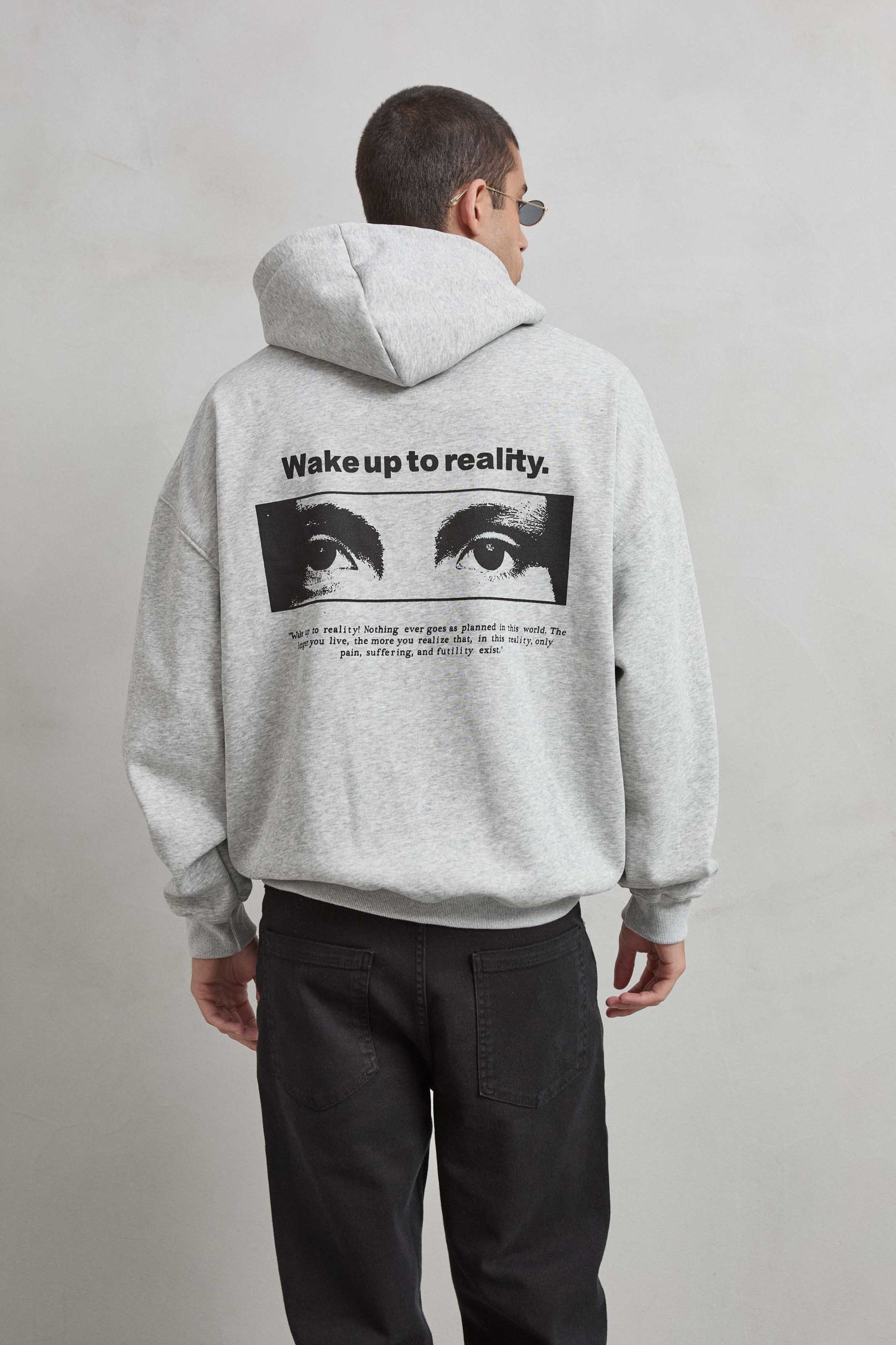 Sudadera gris jaspe con gráfico de ojos y texto “WAKE UP TO REALITY”