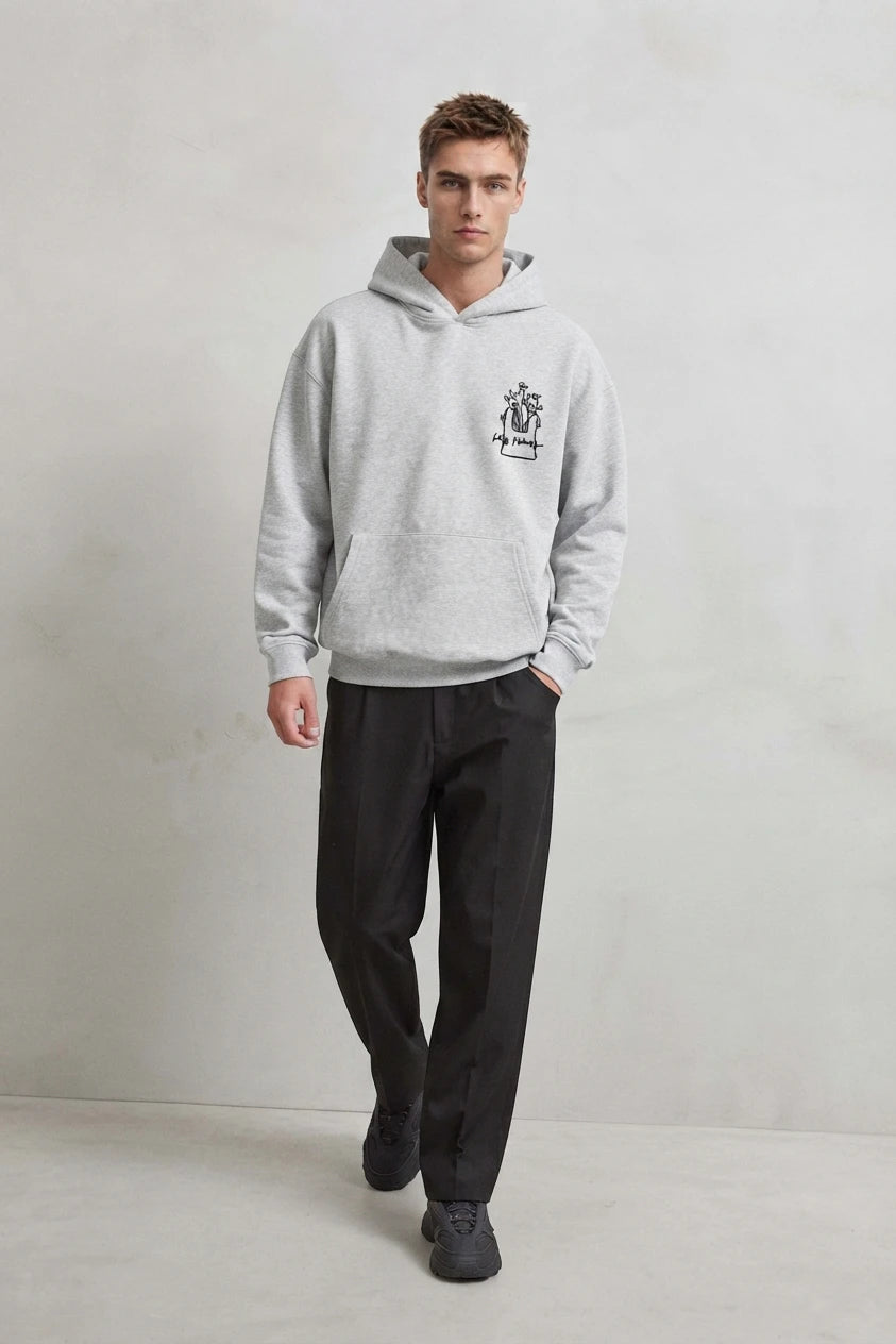 Vista frontal de cuerpo entero con sudadera gris Les Fleurs y pantalones negros