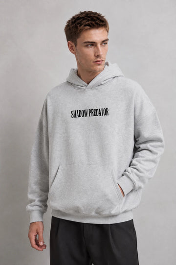 Sudadera gris jaspe oversize de hombre con capucha y texto Shadow Predator, vista frontal