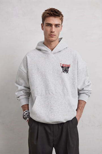 Vista frontal de sudadera gris oversize con bolsillo canguro y pequeño estampado de leopardo