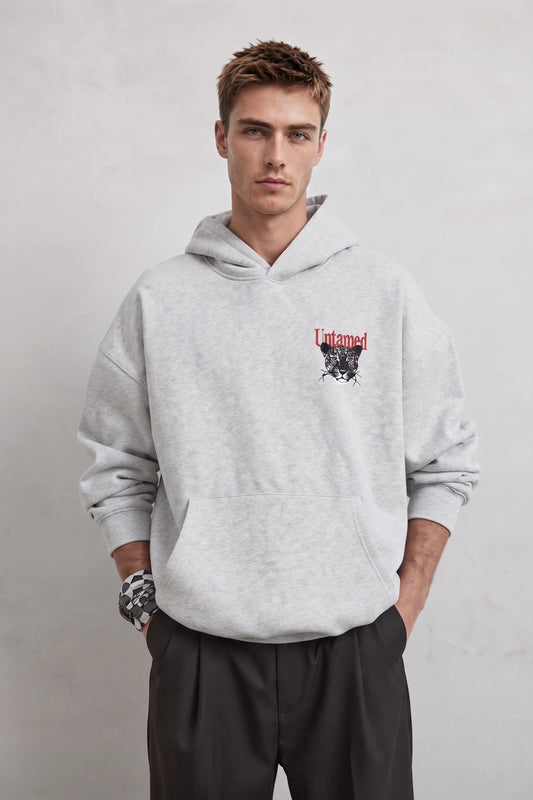 Vista frontal de sudadera gris oversize con bolsillo canguro y pequeño estampado de leopardo
