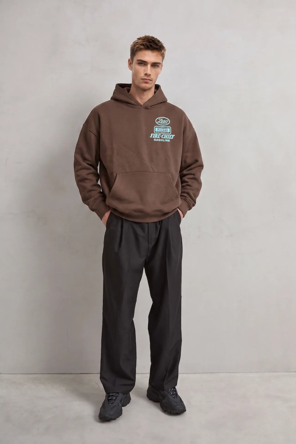 Vista de cuerpo entero con sudadera marrón de estilo racing y pantalones negros