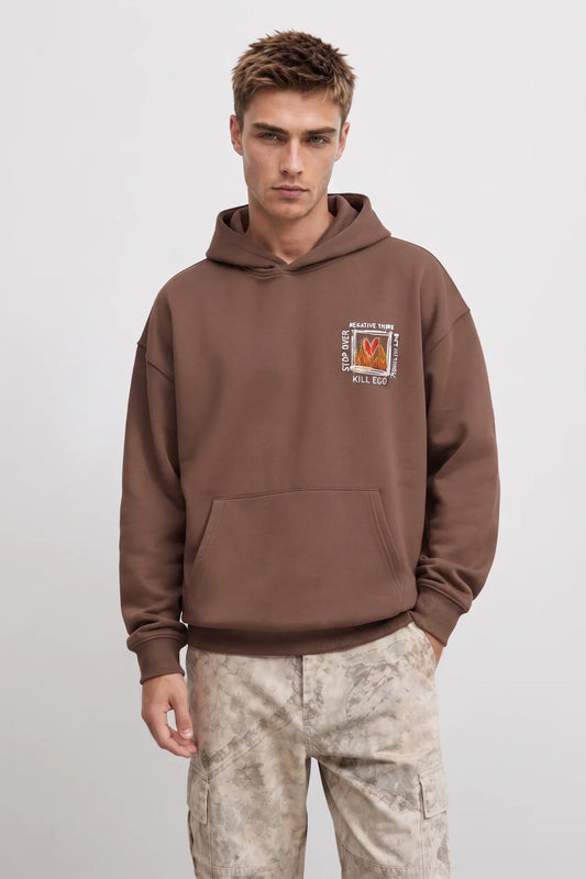 Sudadera marrón oversize de hombre con capucha y pequeño gráfico de corazón rojo entre llamas en el pecho