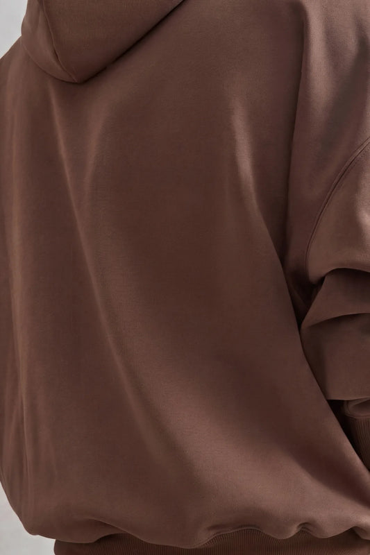 Detalle de la espalda lisa de sudadera marrón con capucha y hombros caídos