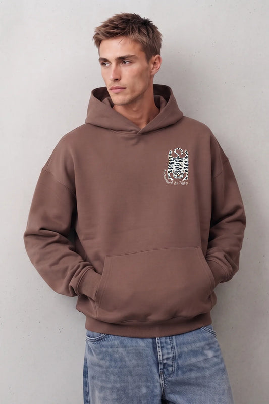 Sudadera marrón oversize de hombre con capucha y pequeño tigre blanco con rayas negras en el pecho
