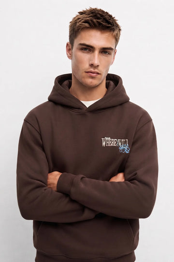 Sudadera marrón oversize de hombre con capucha y pequeño gráfico Where the Wild con flores azules en el pecho
