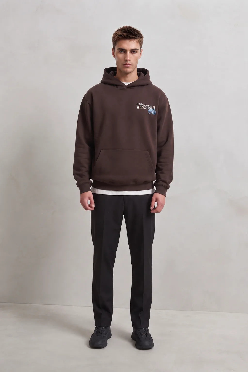 Vista frontal de cuerpo entero con sudadera marrón Where the Wild y pantalones negros